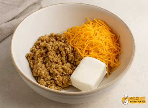 Mixing boudin sausage with cheese and spices in a bowl.