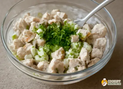 Fresh herbs like parsley sprinkled over the chicken salad, ready for the final mix.